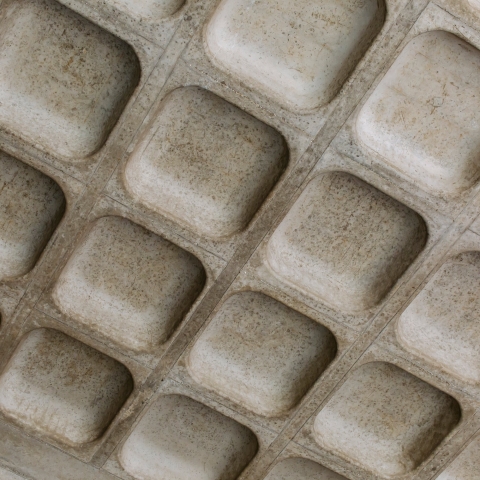 A grey textured surface with uniform rectangular indents.