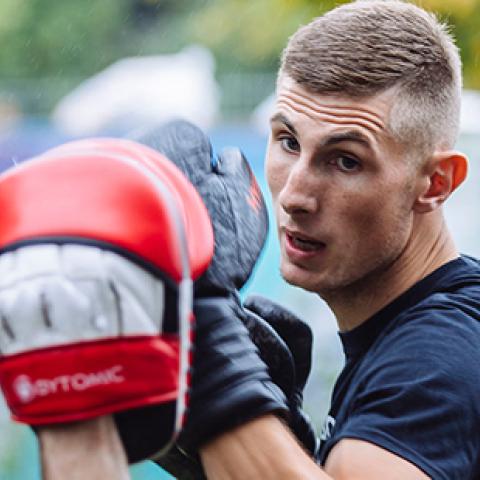 Male boxer training outside with mitts