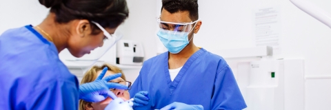 Two dental students work on patient
