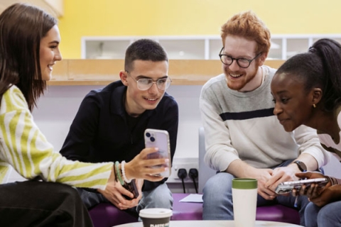 Group of students gathered around a table looking at a phone