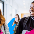 Two students smiling in a university building with colourful splashes around them